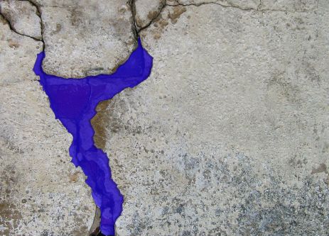 Close-up of bright purple detailing in a crack in a concrete wall