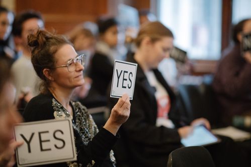 A woman holds a card that says 'yes'