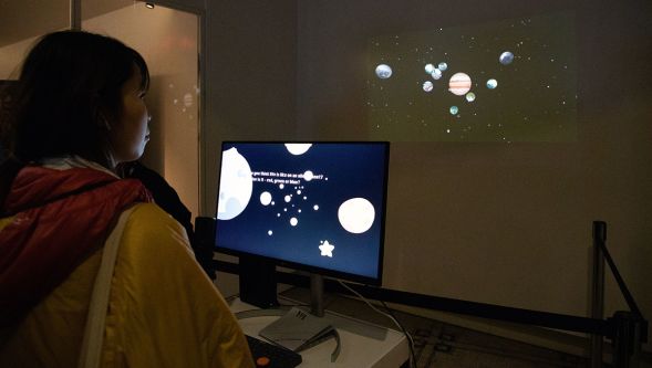 A visitor watches a wall-projection of the solar system.