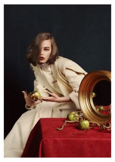 Female model wearing a cream suit sat on a red cloth