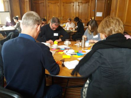 Groupwork around a table, writing on brightly coloured post it notes