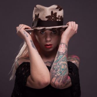 Girl wearing a light brown felt hat with flower design.