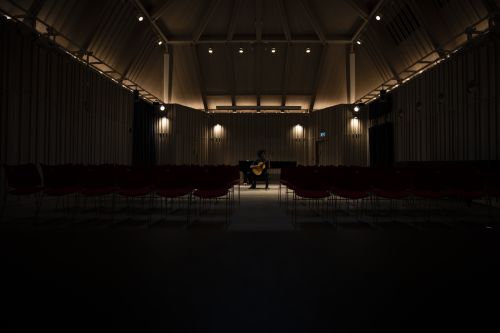 theatre in darkness with dim lights and man playing guitar on the  stage