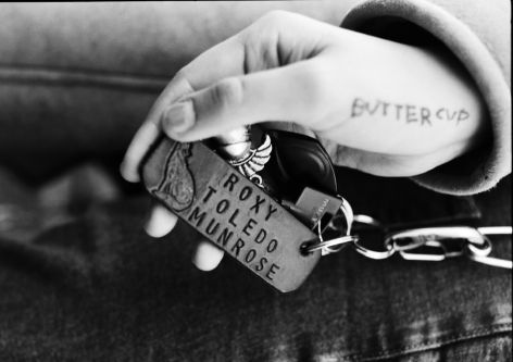 Close up shot of a hand holding a dog tag that reads 'Roxy Toledo Munrose'