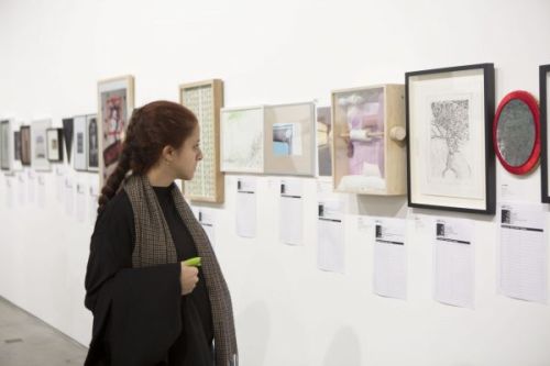 Photograph of a woman looking at the installed work in the gallery