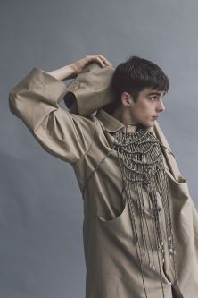 Male model wearing camel coat and crocheted necklace