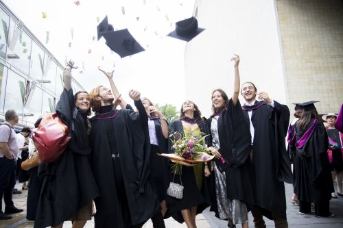 Student throwing mortarboards into the air