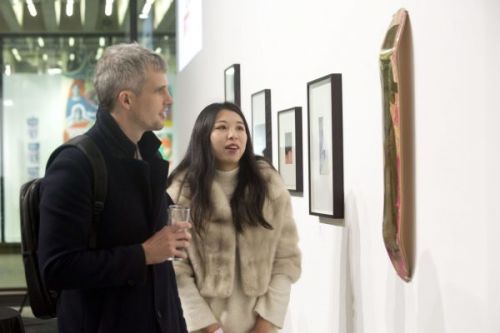 Two people looking at artwork hung on the wall of the gallery