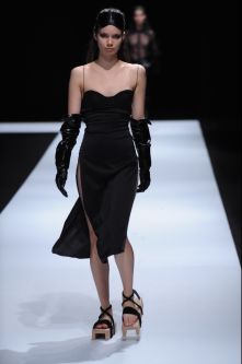 Female model wearing black dress designed by Emilija Vaisnoraite