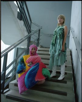 Two models in Emily's fashion designs. They are colourful, long dresses.