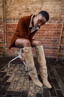 Model wearing tan jacket modelling knee high leather beige boots
