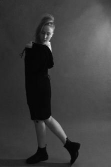 Model in black shirt dress posing with back to the camera in black and white backdrop