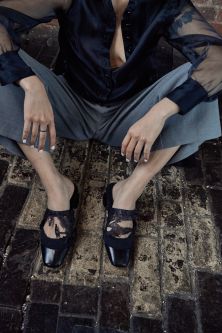 Cropped shot of feet and hands modeling black mules