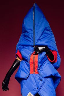 Model wearing blue dress with face hidden by big hood, made out of recycled tents