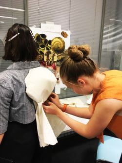 Mandula Pap working with model, tying material to model's clothing.