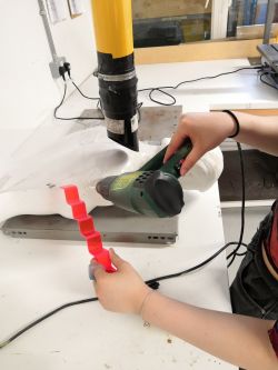 A person's hands working with materials and a drill