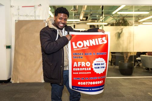 Manager Henock unpacking the designs, a poster and a signage, on behalf of Lonnies International hairdressing owner, Betty Adave-Asafu.
