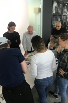 people standing around a table with images on it