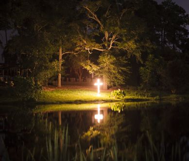 a cross on fire reflected on a lake