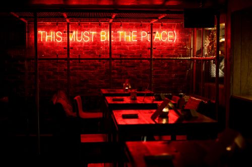 a red light reading this must be the place shines into a restaurant 