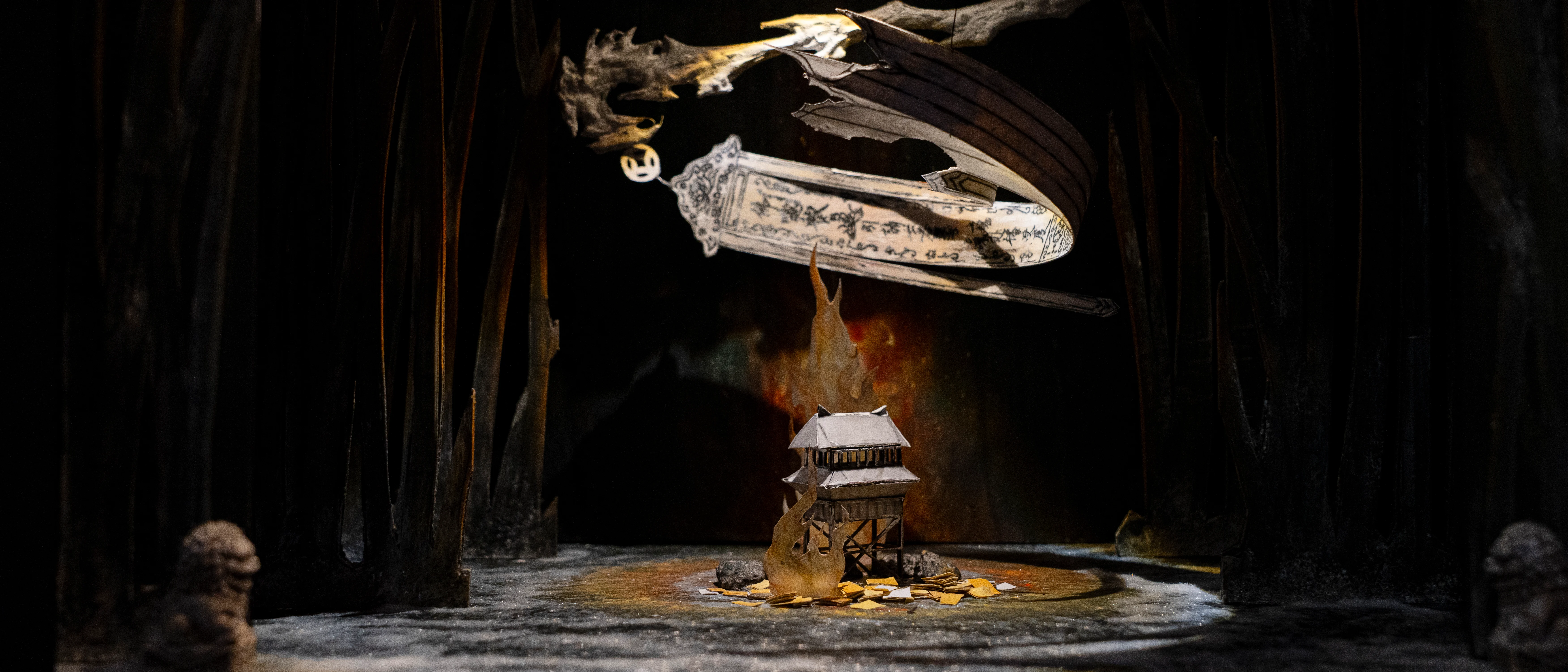 A shadowy, mystical scene depicts a small house on a rock amid dark, towering trees. Above, a ghostly, ornate figure floats, enhancing the eerie atmosphere.