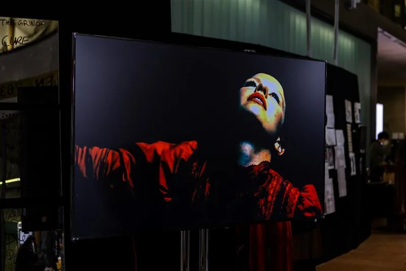 An close-up on a large screen of a person's upturned face and arms stretched out with red sleeves