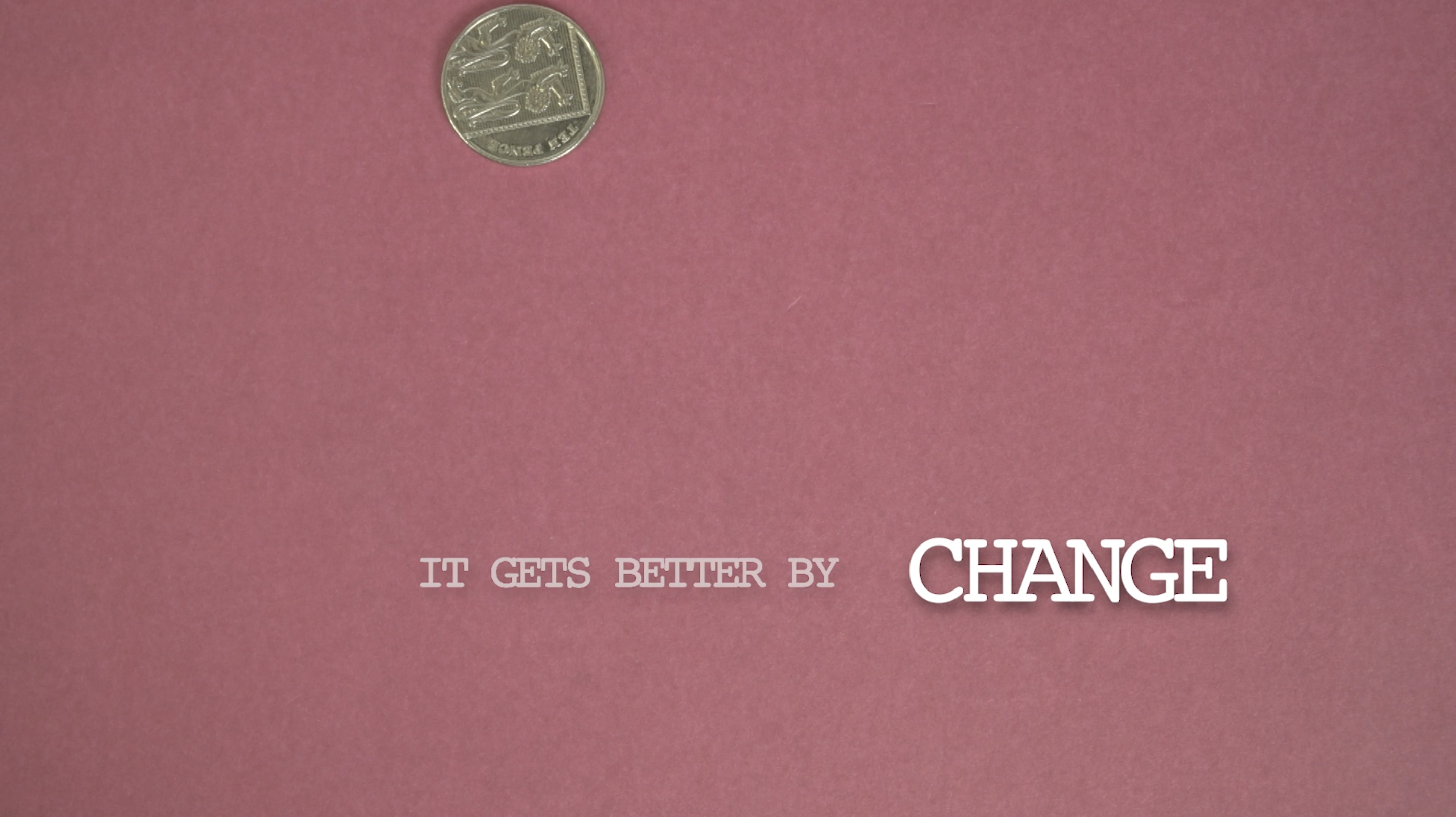 A still of a coin falling in front of a pink background.