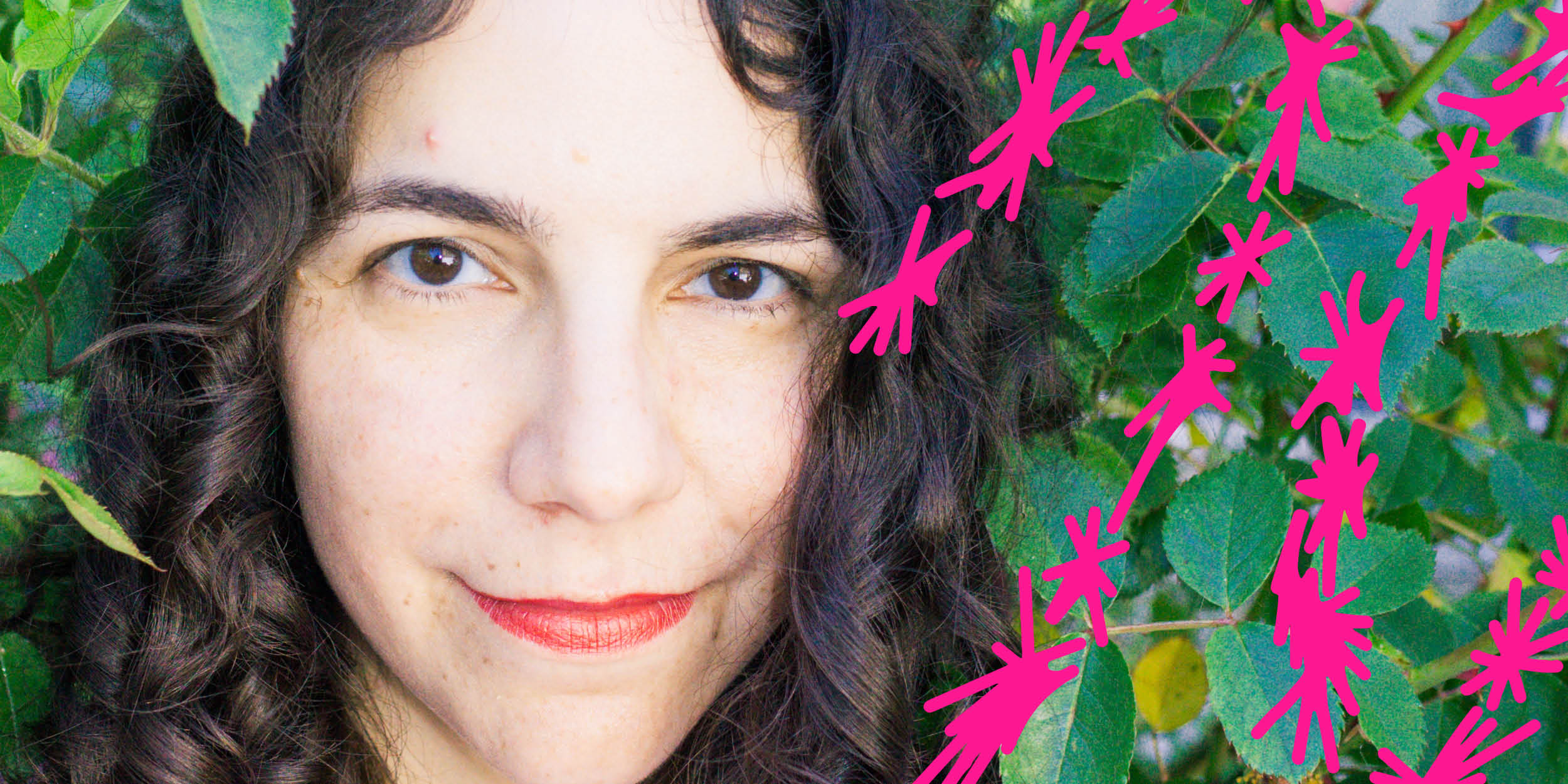 a person's face looking at the camera surrounded by green foliage