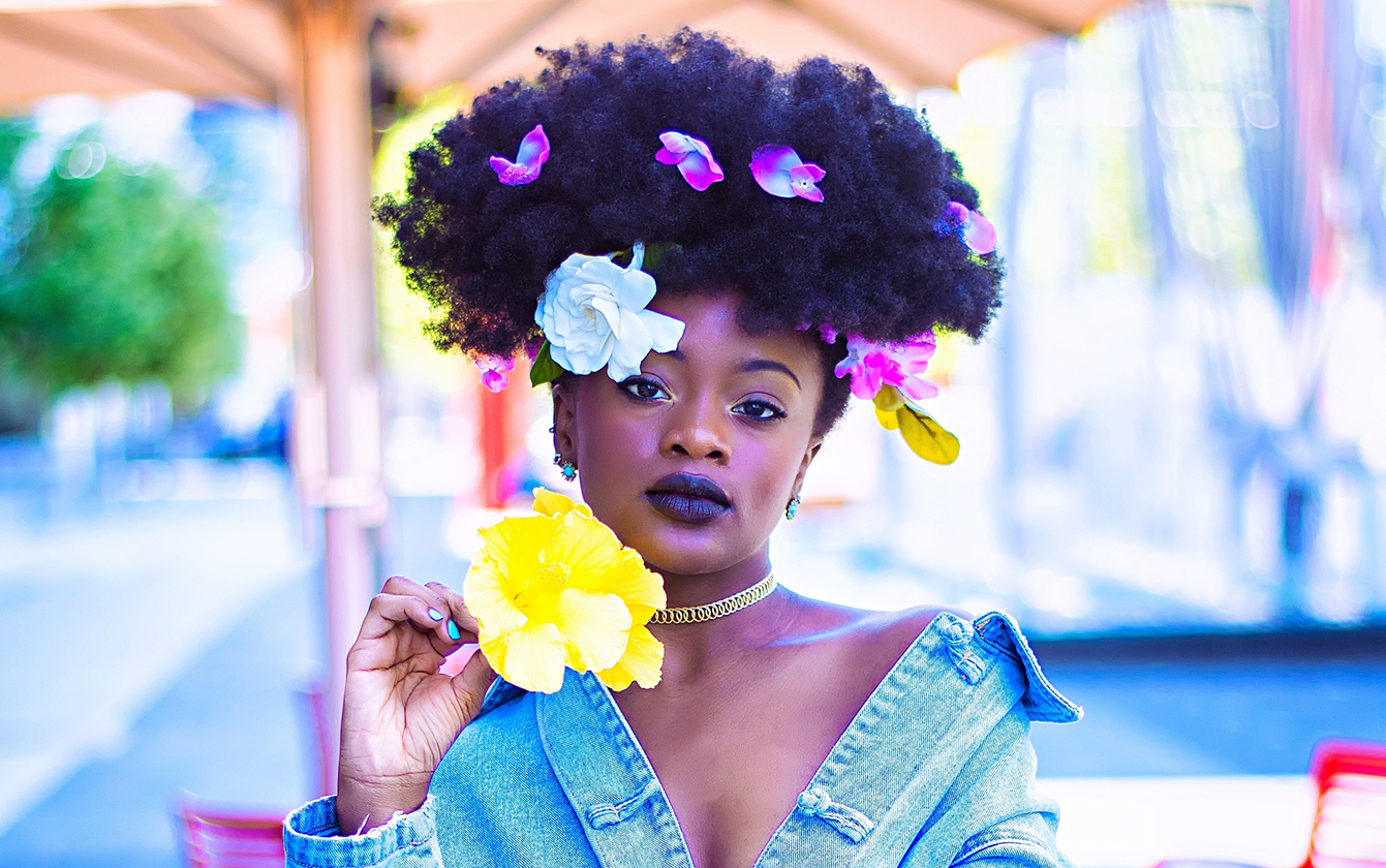 Female model posing with flowers in her hair and denim jacket