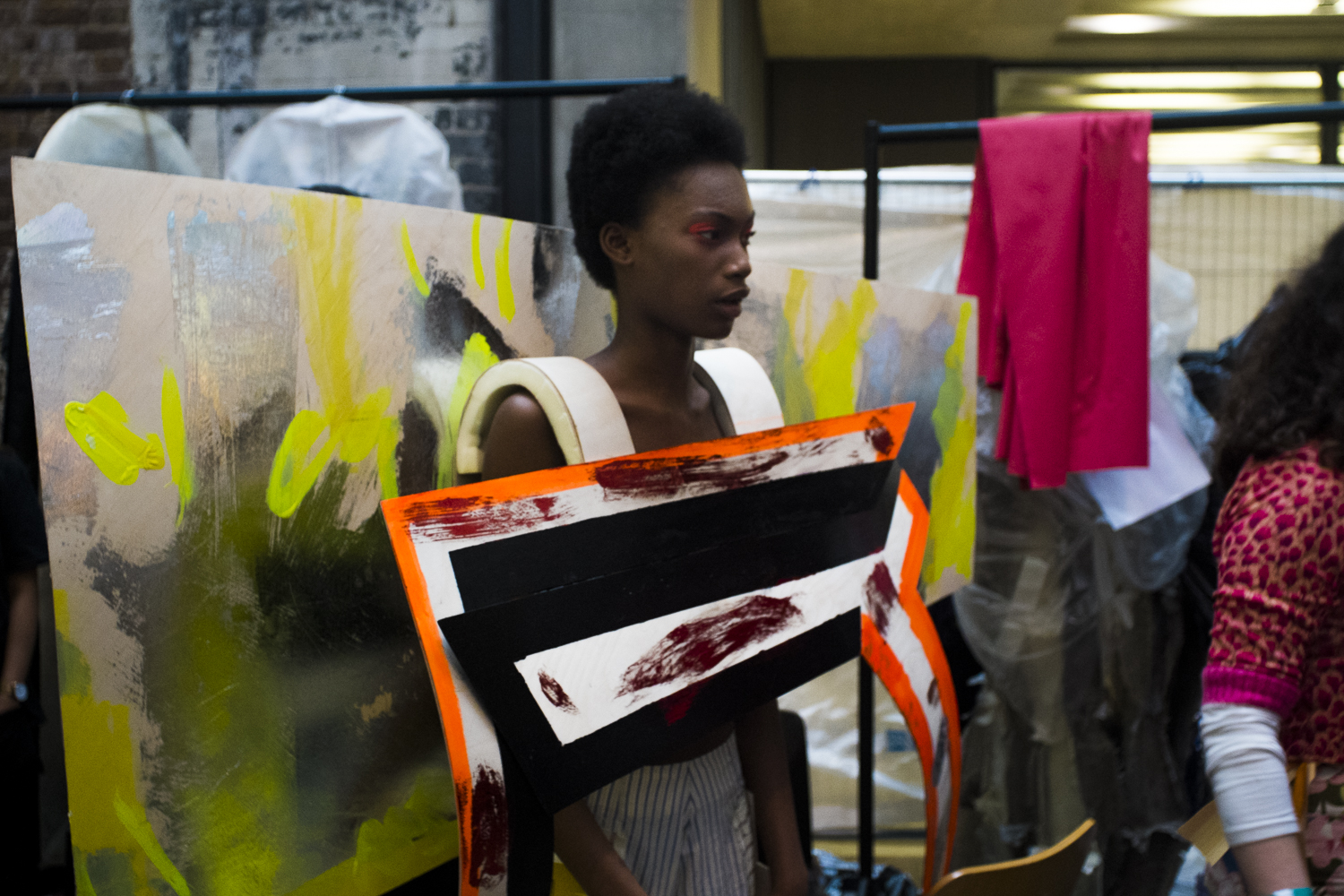 A model standing in front of a printed and painted background 