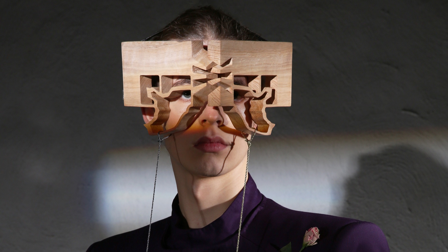 Butterfly-shaped wooden eyewear modeled by male in purple suit.