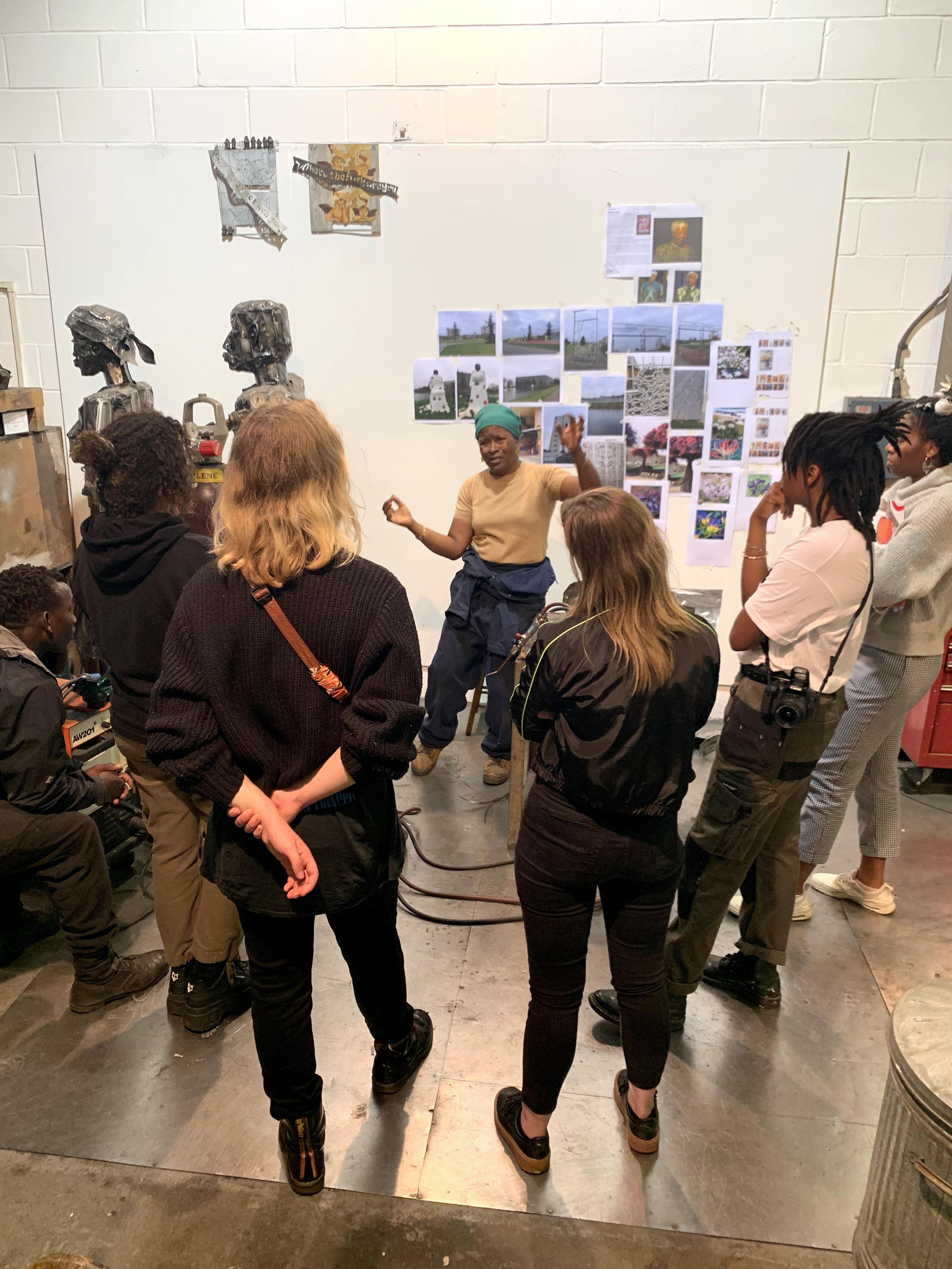 A group of students inside the artist Sokari Douglas Camp's studio which is full of photographs and sculptures