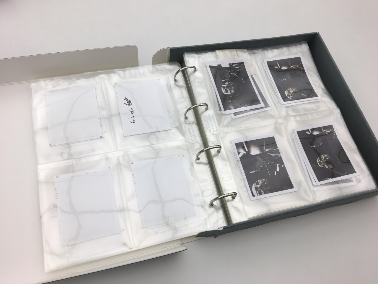Folder of black and white photographs in archival packaging.
