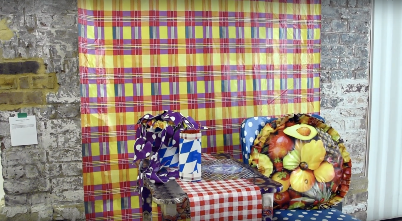 An installation view of a set of table and chairs that are covered in a brightly coloured plastic material