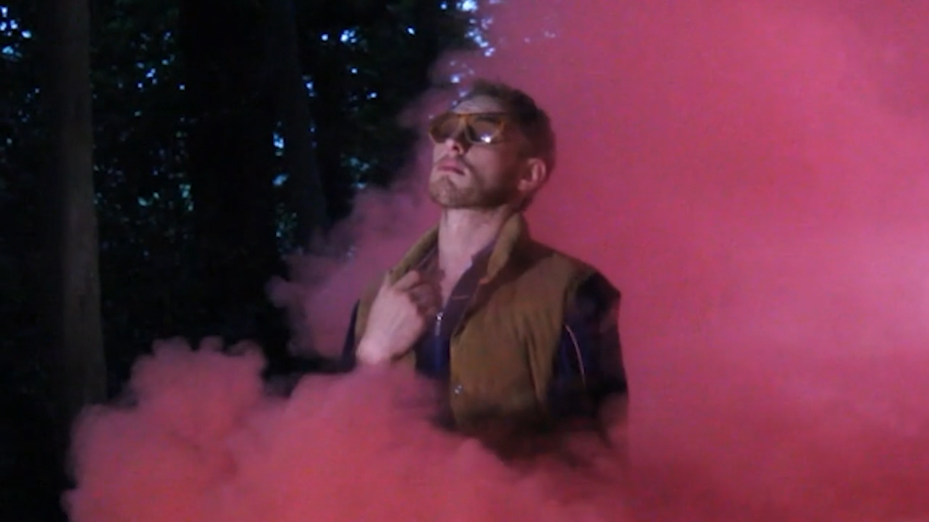 Luke Abbott stood among red smoke wearing sunglasses.