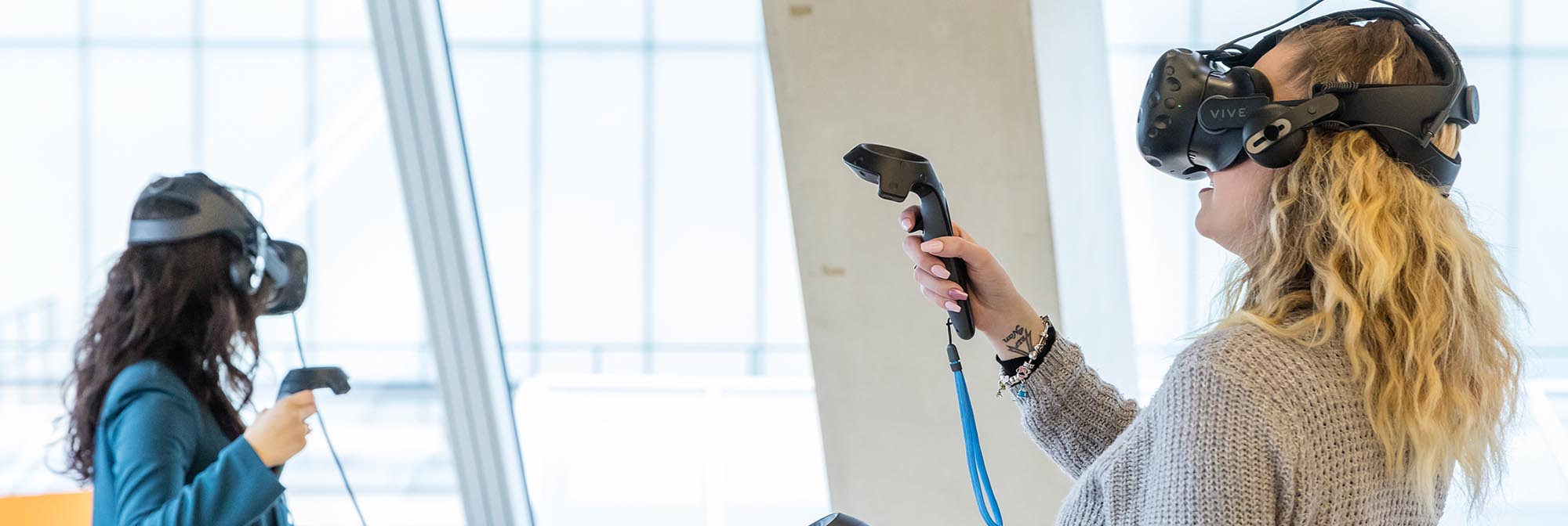 Two women wearing virtual reality headsets.