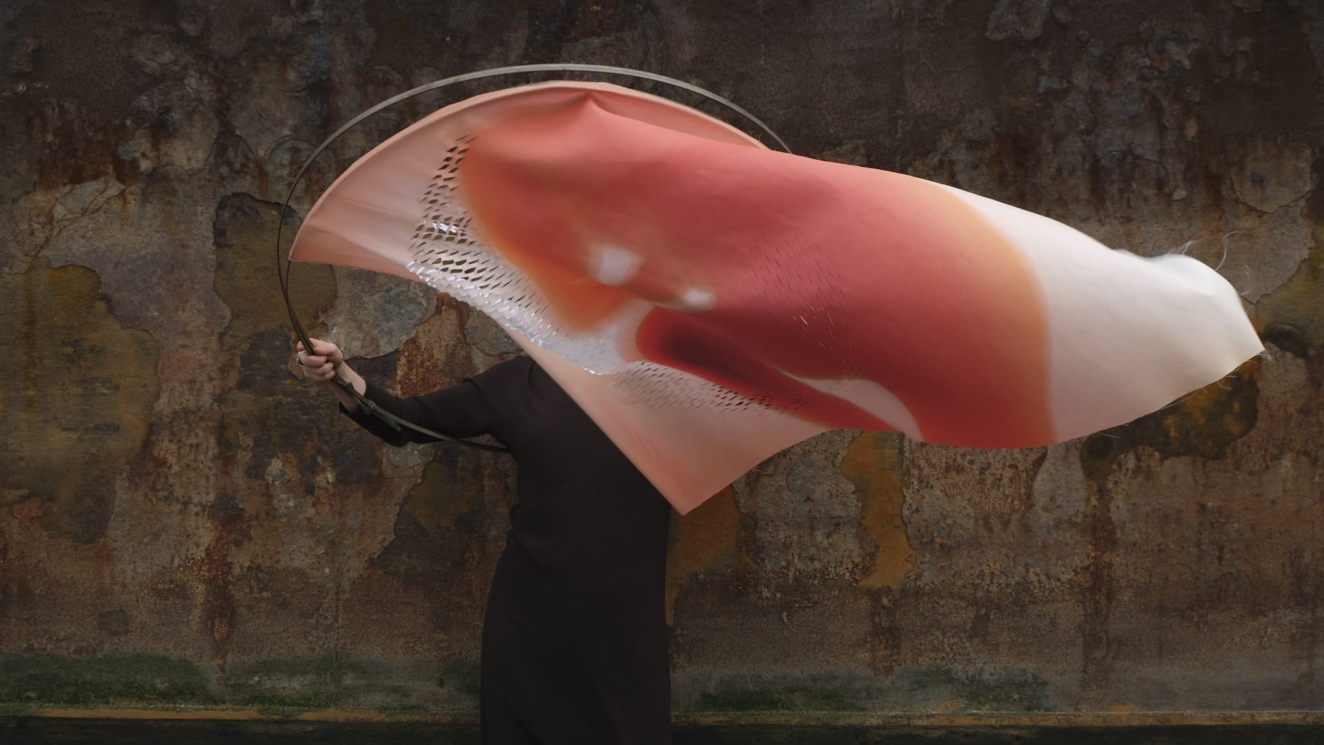 Figure holding up red and pink textile