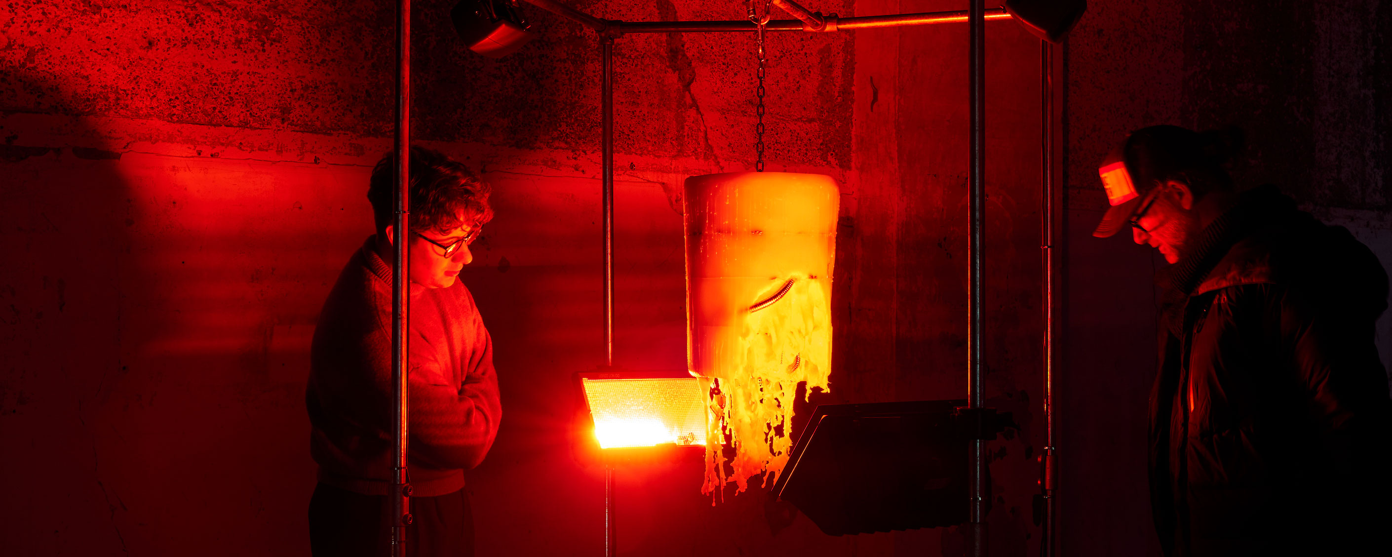 Two people look at a sculpture under a red light.