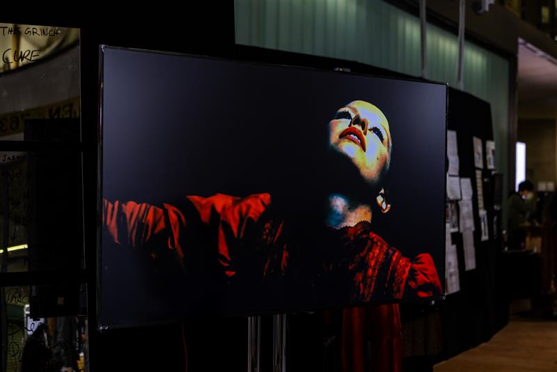 An close-up on a large screen of a person's upturned face and arms stretched out with red sleeves