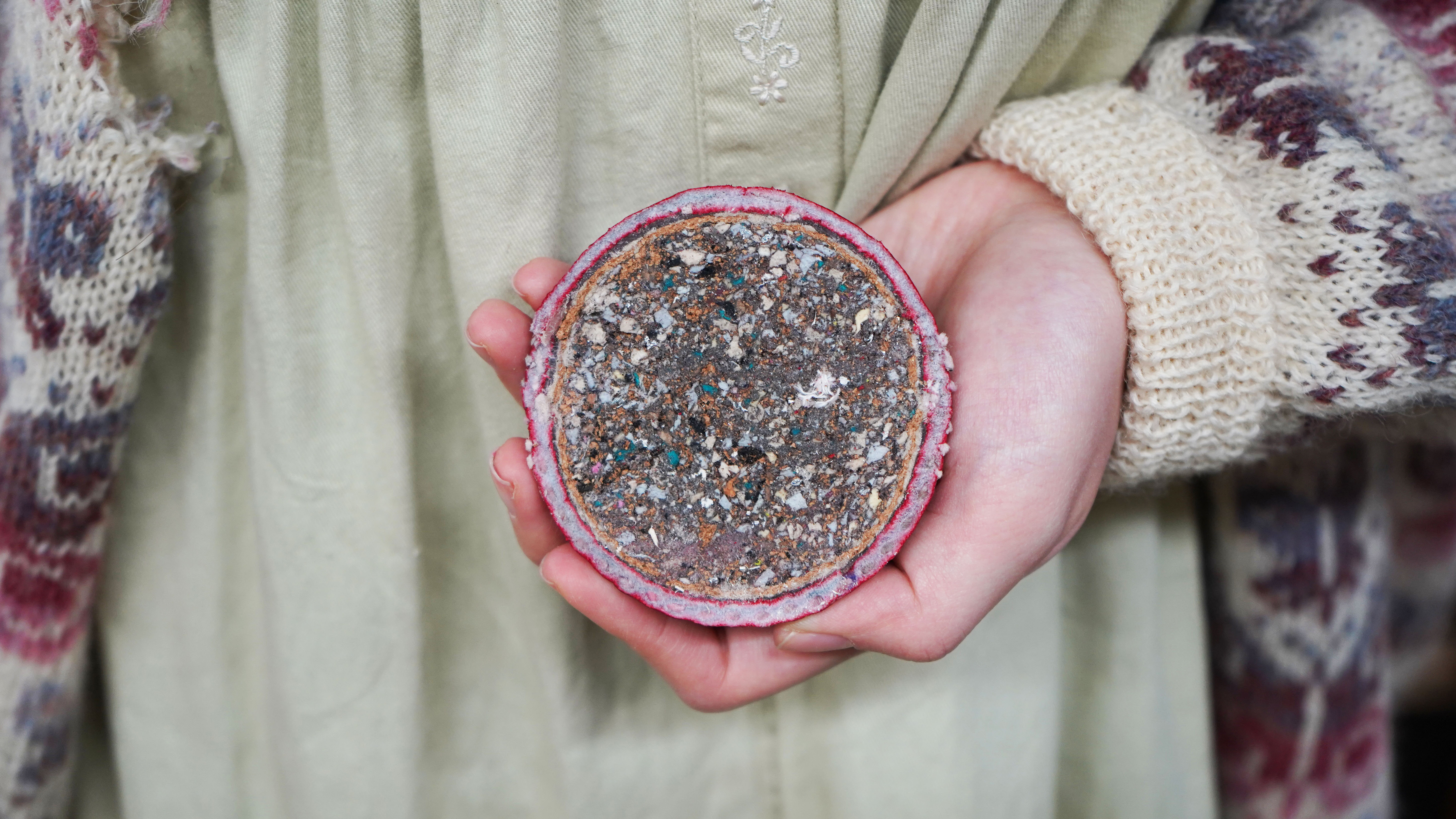 Student holding model that has been sliced in half to reveal inside showing recycled filling.