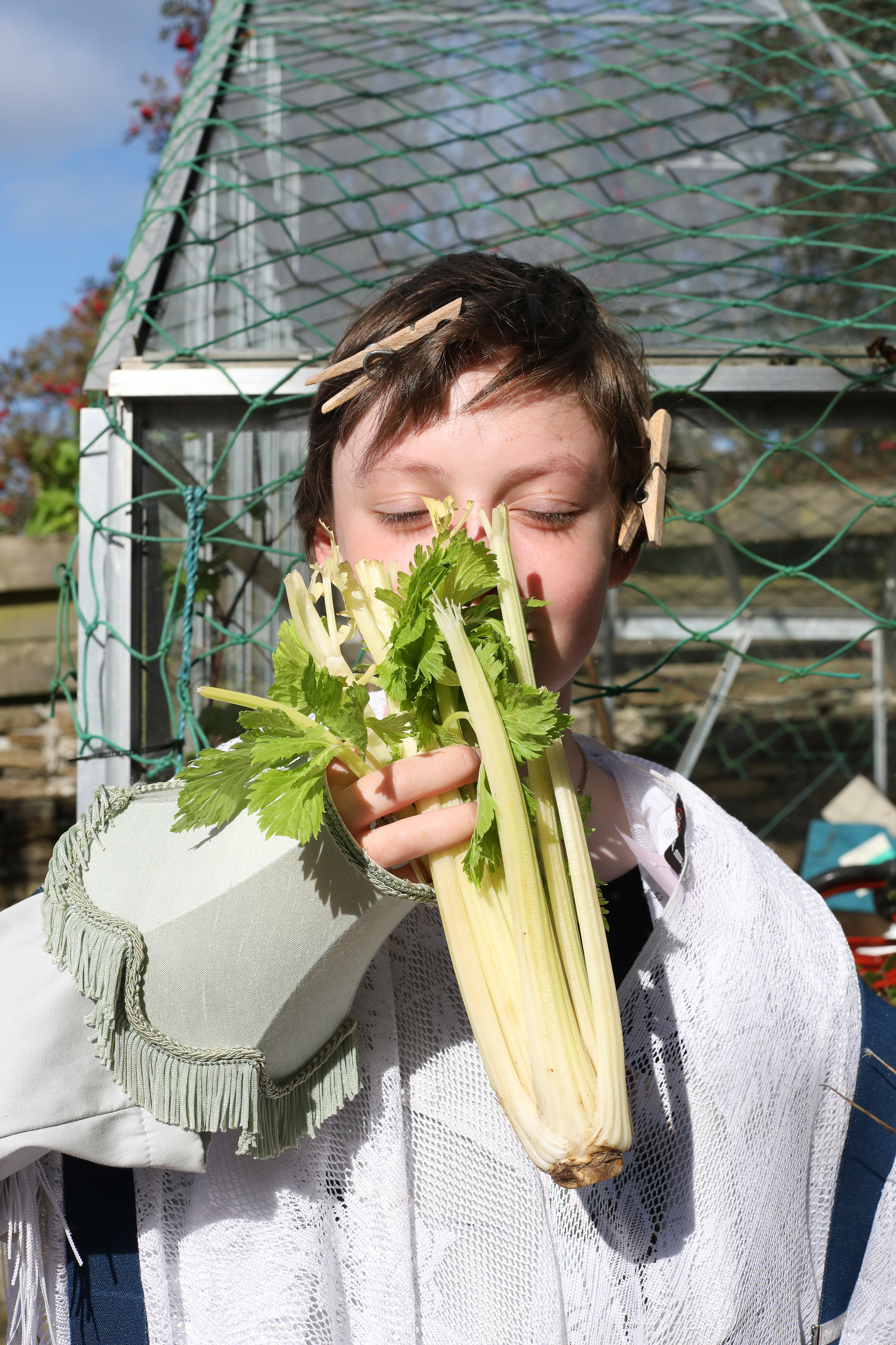 A girl holding a vegetable in front of her face 
