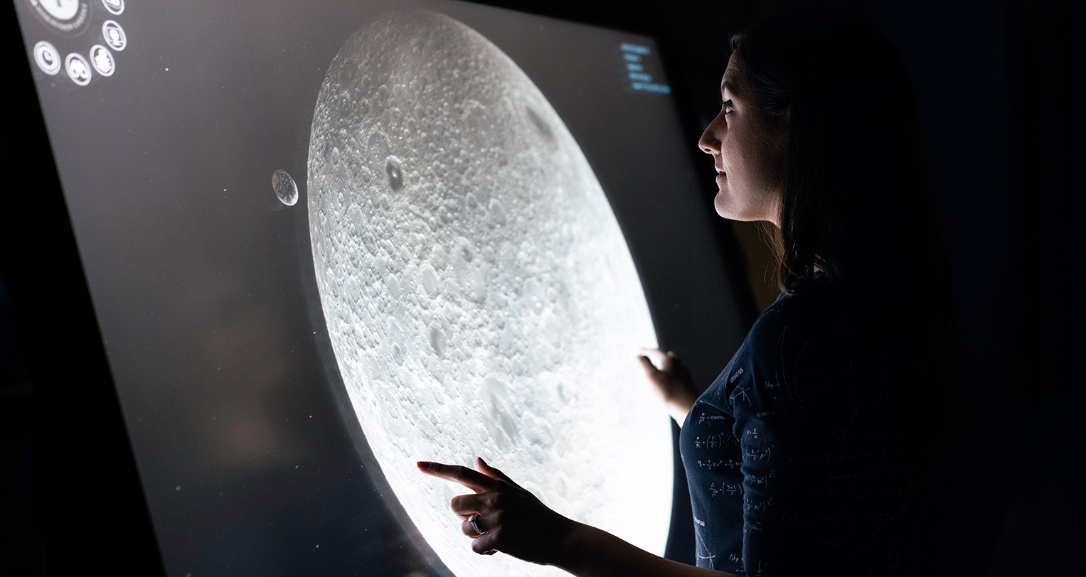 A girl stands beside a glowing map.