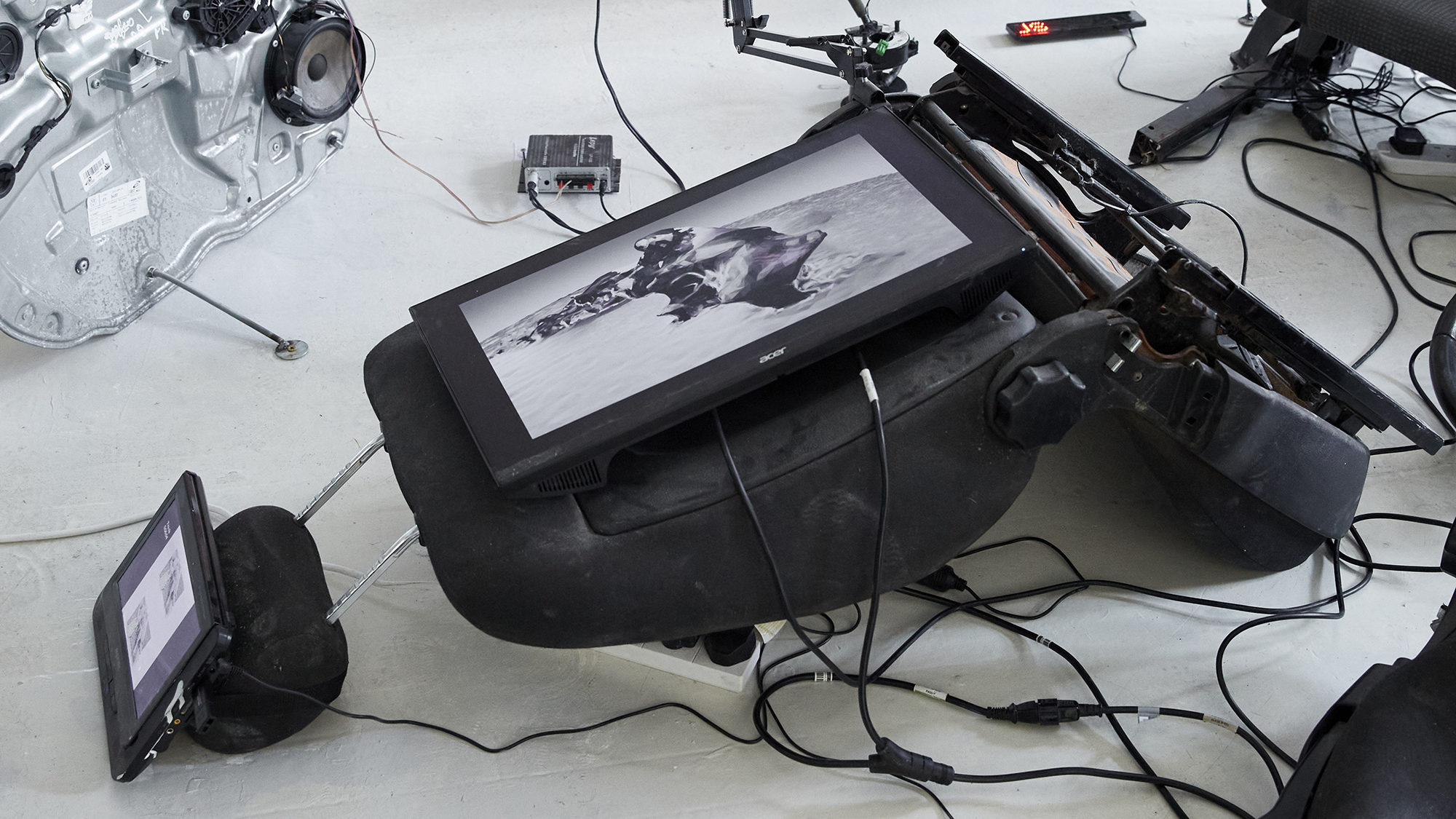 Car parts broken up across the gallery floor with digital screens added and inserted playing black and white images. Installation by Livia Harper - BA Fine Art
