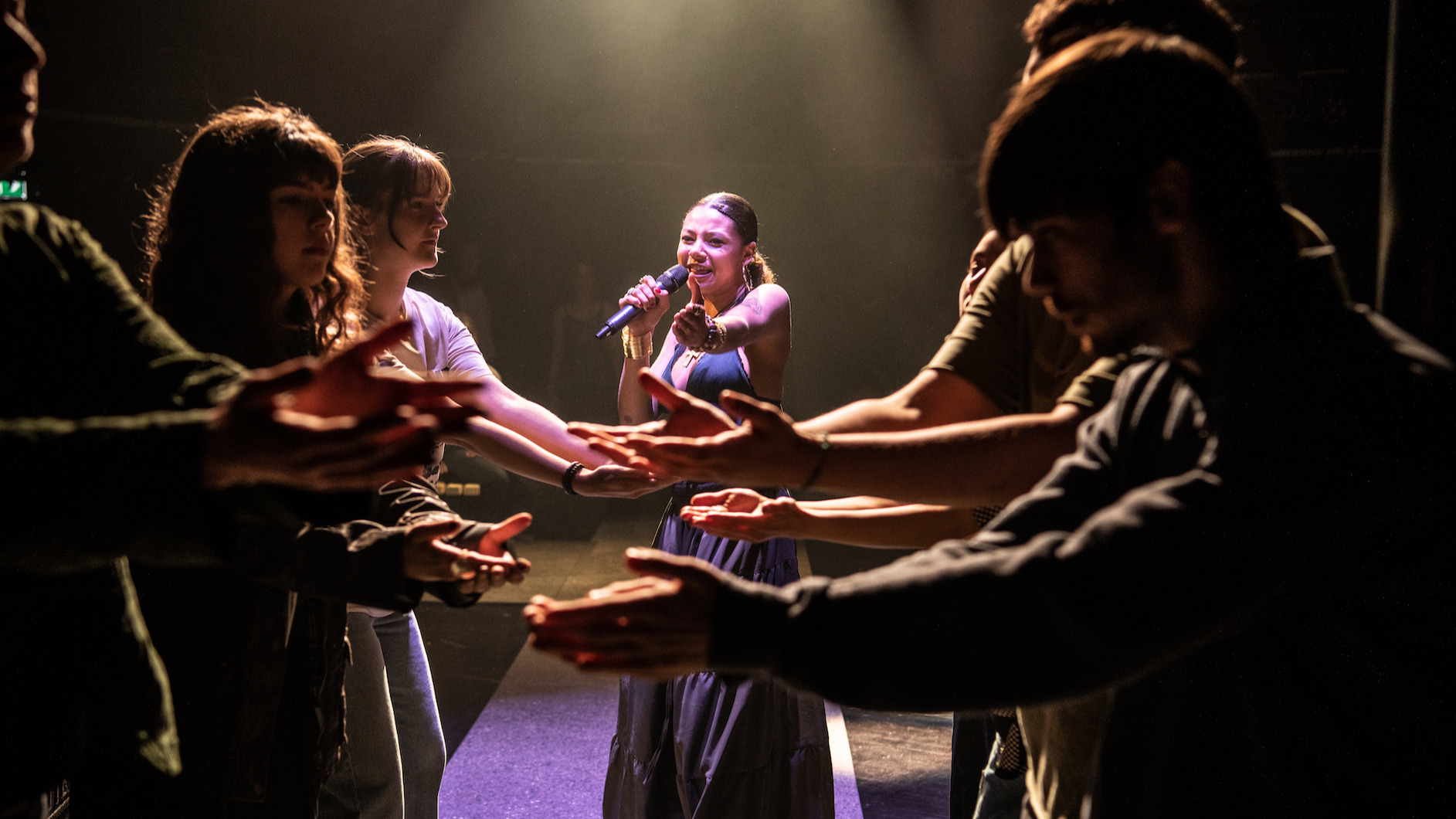 A group of performers holding their arms towards each other