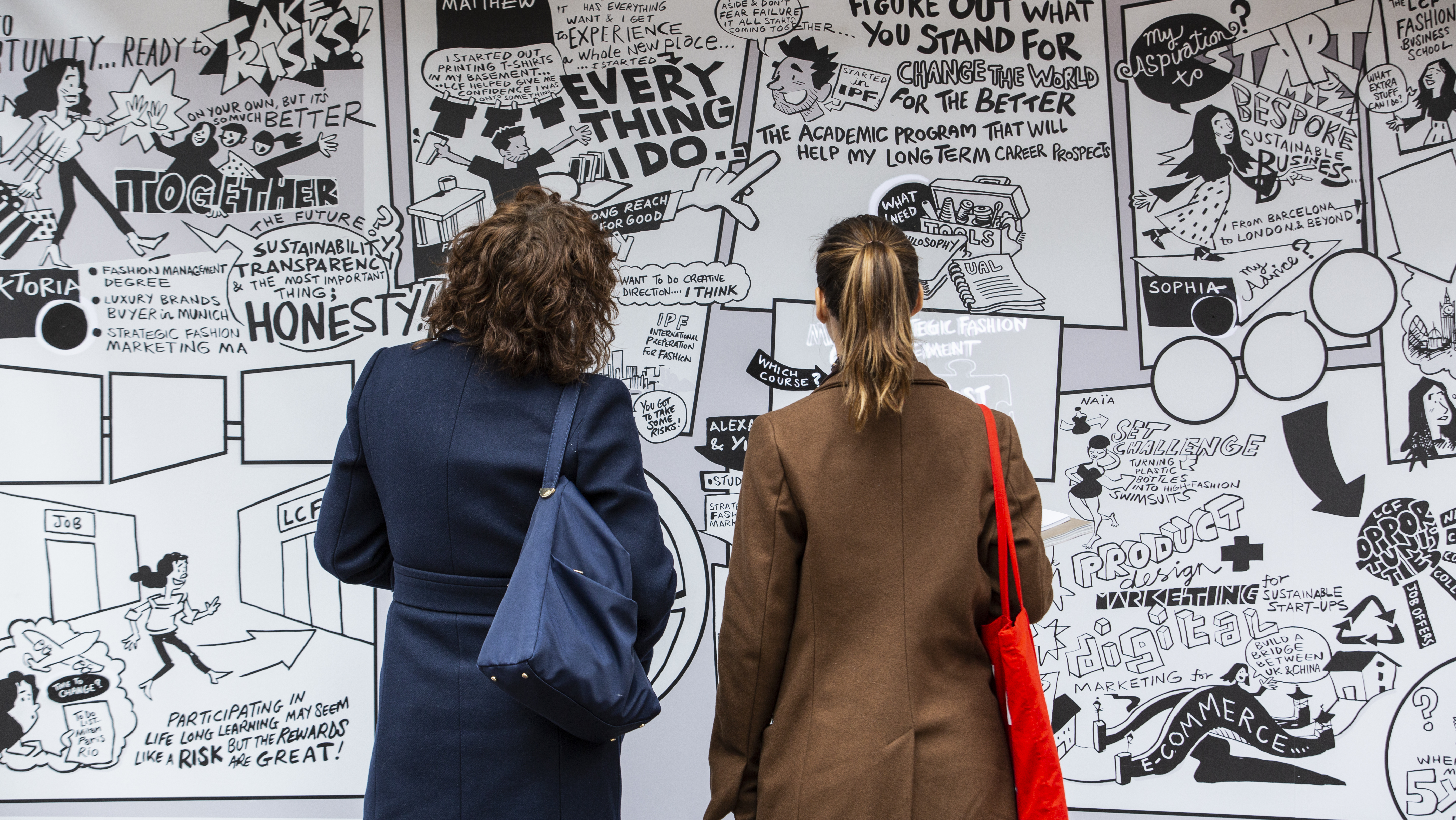 Two people standing up in front of a poster during an exhibition