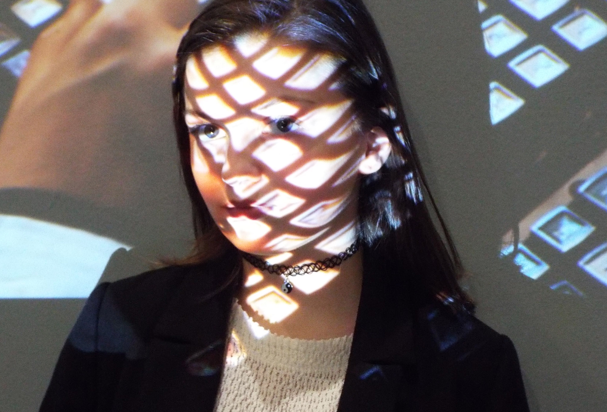 a portrait of a person in front of a projector, projecting a grid pattern onto their face