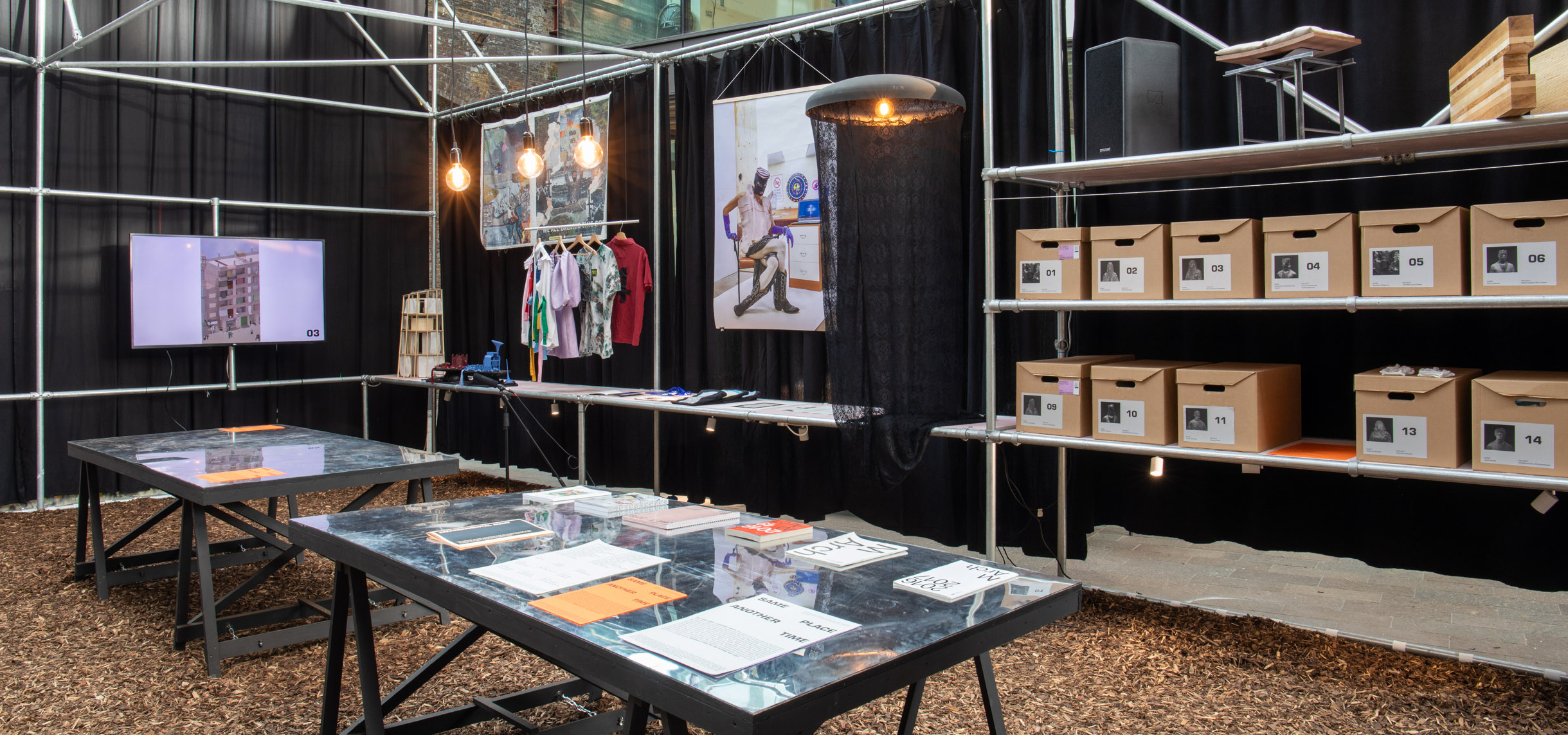 An exhibition display featuring publications, posters, boxes and clothing