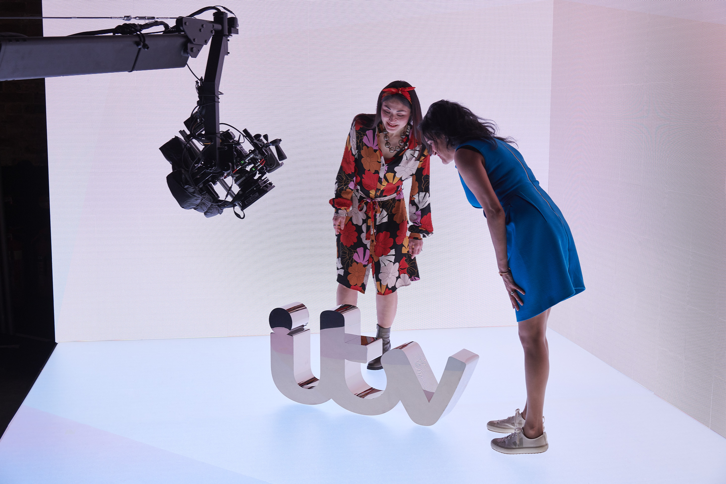 Two women setting up a shot of the mirrored model of the 'itv' logo