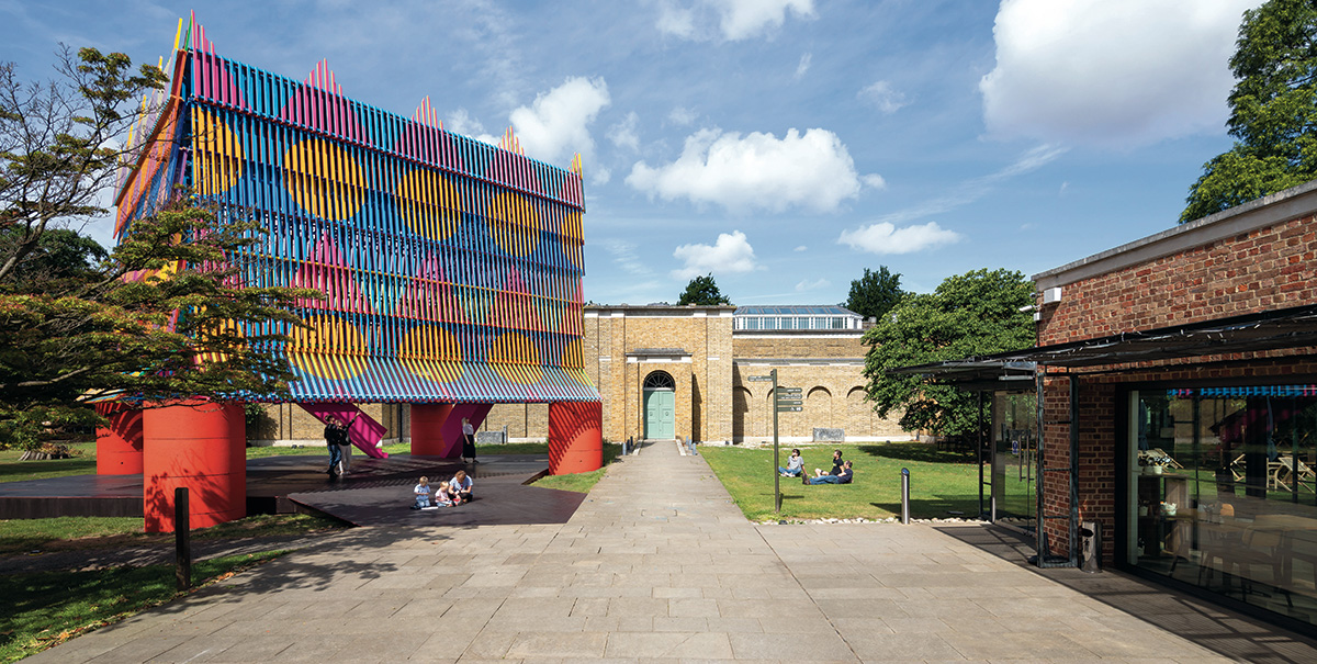 Image depicts a brightly coloured structure, the Colour Palace, erected in front of Dulwich Picture Gallery.