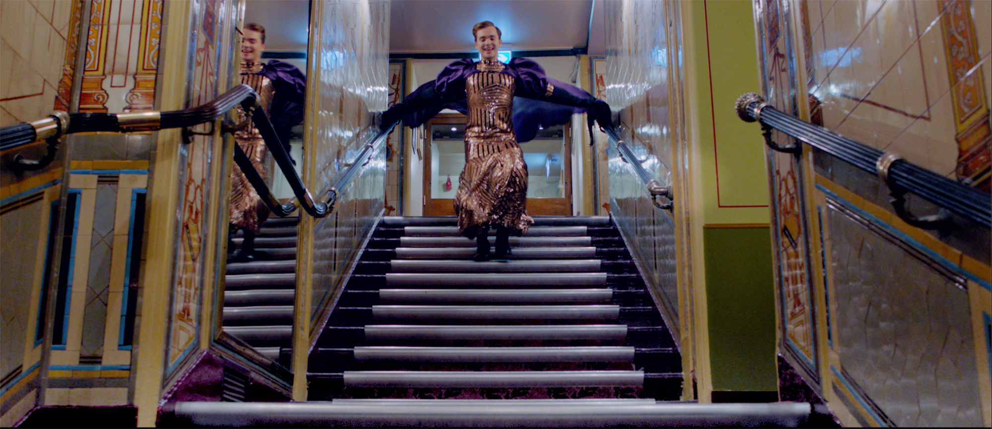 A figure leaps down a staircase within a lavish interior.